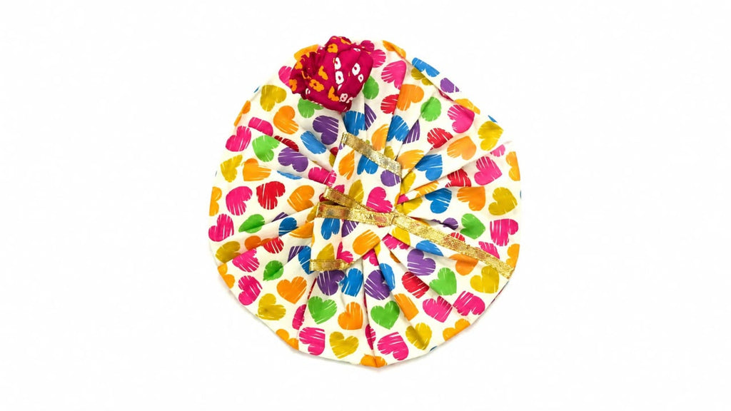 White Laddu Gopal poshak with vibrant heart prints, golden lace, and matching maroon pagdi.