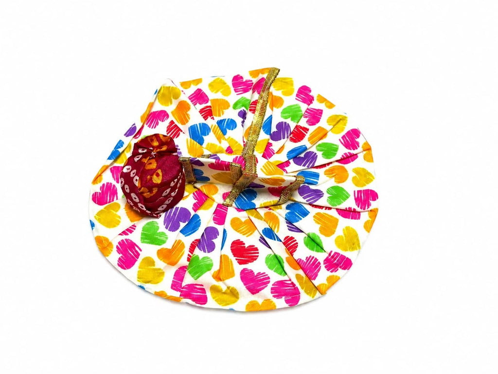 White Laddu Gopal poshak with vibrant heart prints, golden lace, and matching maroon pagdi.